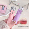 Pink and purple lip glosses with butterfly designs held by a hand, close-up view.