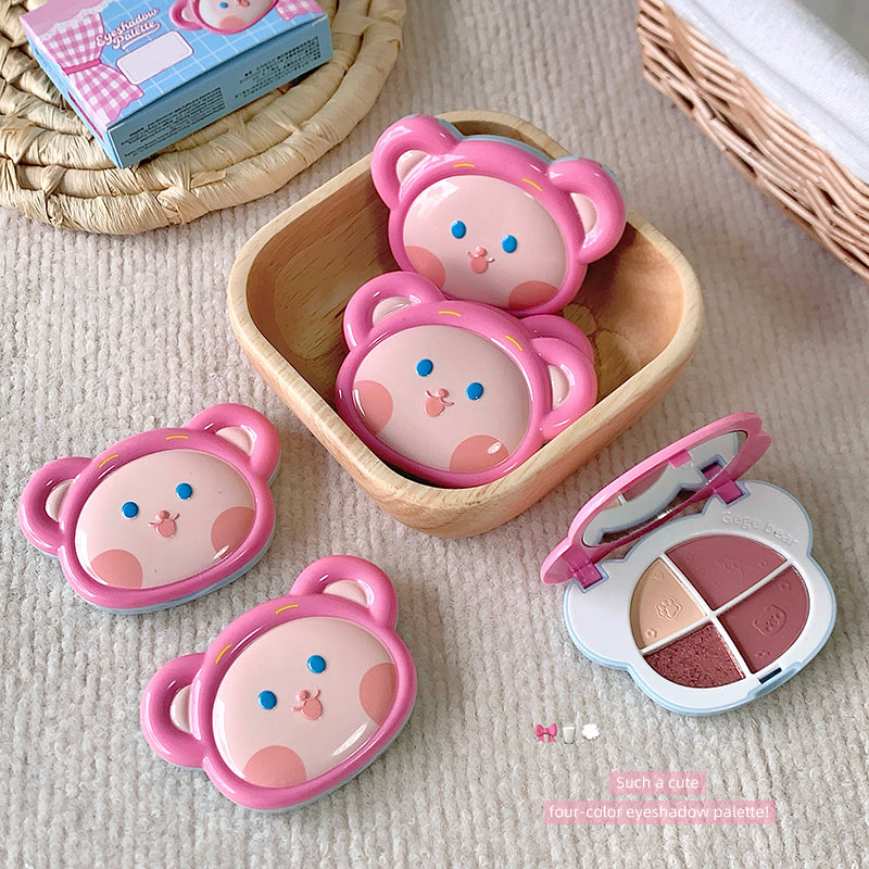 Set of pink bear-shaped makeup cases with a compact mirror on a beige surface.