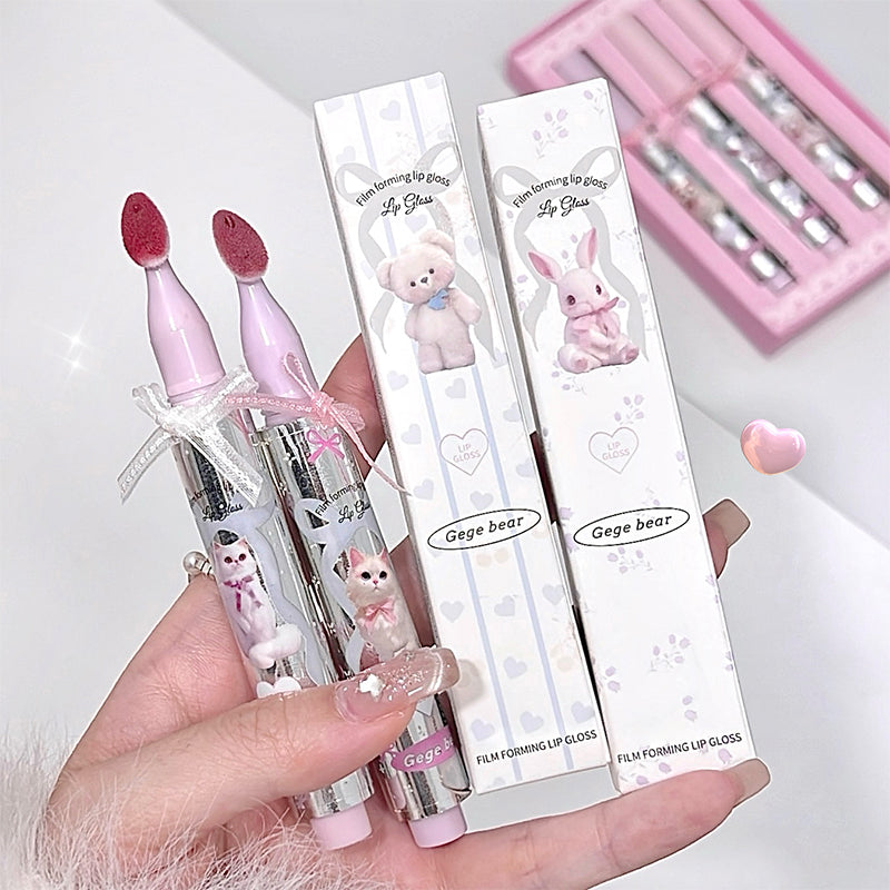 Two lip glosses with cute animal designs in their packaging held by a hand.