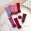 Collection of GEGE BEAR lip balm tubes on a white plate with a patterned cloth in the background.
