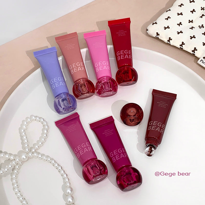 Collection of GEGE BEAR lip balm tubes on a white plate with a patterned cloth in the background.