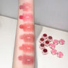 Lipstick swatches on an arm with six different shades and a set of lipsticks in pink cases.
