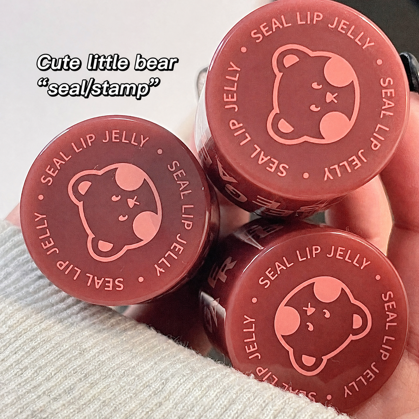 Three red lip jelly containers with a bear design on a light gray background