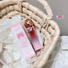 Pink perfume bottle and packaging on a textured surface with '#bow!' text.