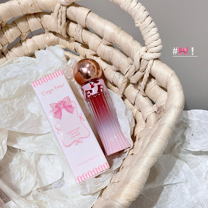 Pink perfume bottle and packaging on a textured surface with '#bow!' text.