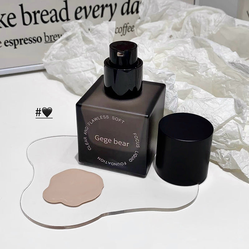 Black cosmetic bottle with applicator on a white surface