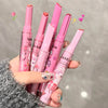 Set of pink lip products with cartoon designs held by a hand against a gray background.