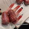 Two red lip balm tubes with 'GEGE BEAR' branding on a hand with red nail polish.