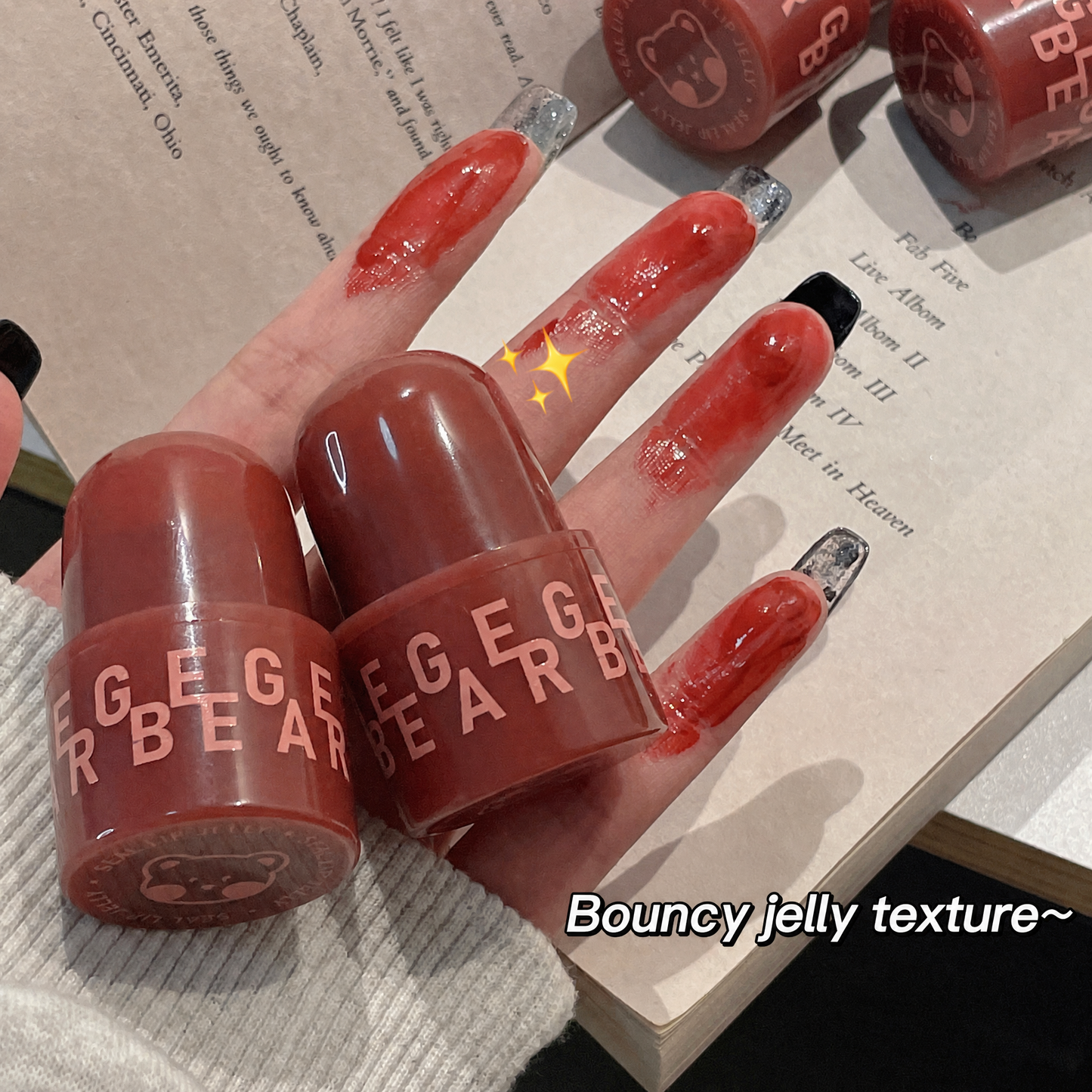Two red lip balm tubes with 'GEGE BEAR' branding on a hand with red nail polish.