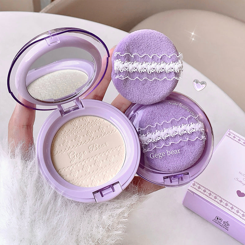Purple makeup compact with a mirror and another compact on a white surface.