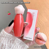 Lip balm with bear-shaped cap held by a hand, next to its packaging on a wooden surface.