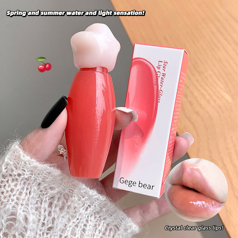 Lip balm with bear-shaped cap held by a hand, next to its packaging on a wooden surface.
