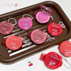 Set of GEGBEAR lip products on a brown tray with cherry graphics.