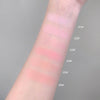 Color swatches of blush on a person's arm with labeled shades against a gray background