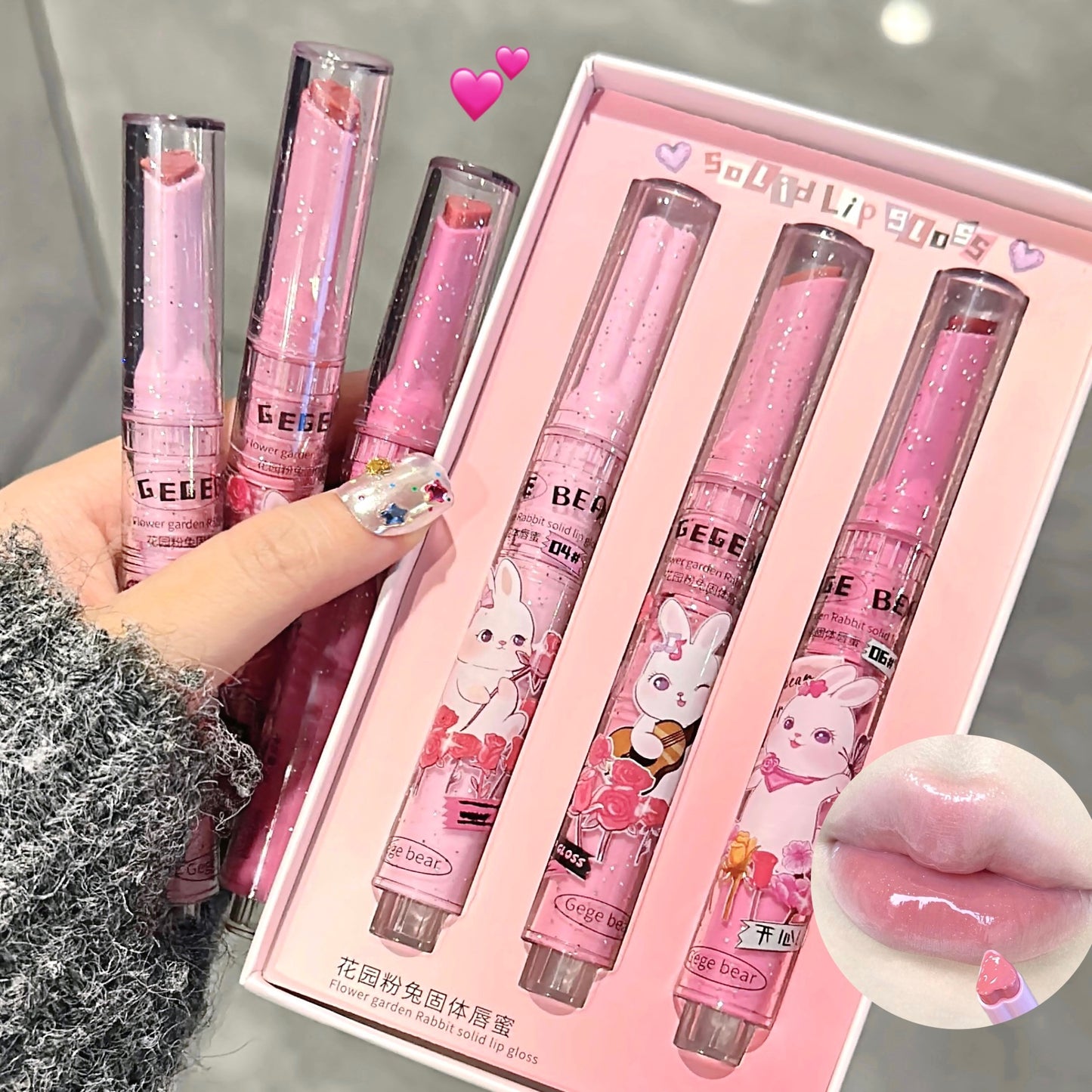 Set of pink lip products with cartoon designs in a box, held by a hand.