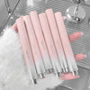 Set of gradient pink lip glosses held by a hand on a reflective surface.