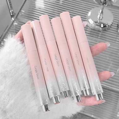 Set of gradient pink lip glosses held by a hand on a reflective surface.