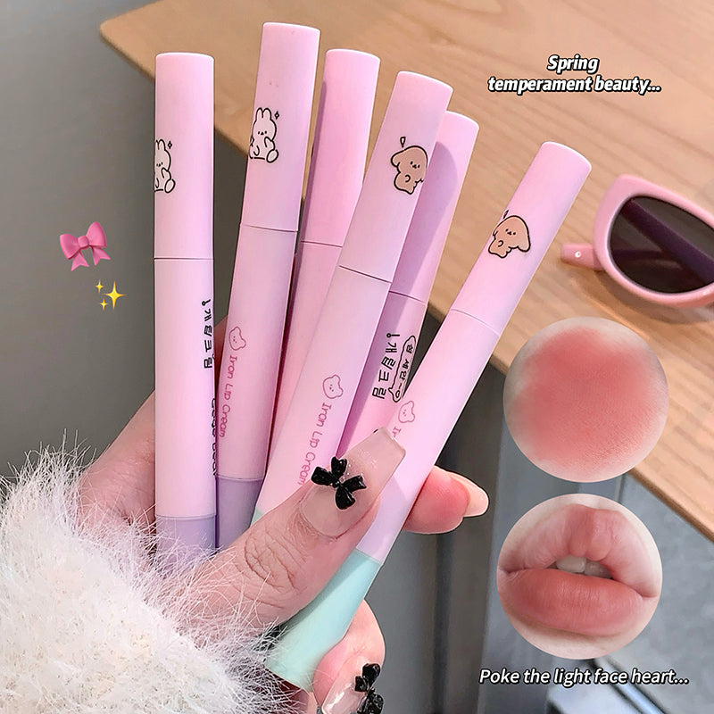 Set of pink lip glosses with cute designs held by a hand, on a neutral background.