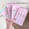 Set of pink lip cream products with a hand holding them, on a neutral background.
