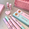 Set of pink and green stationery items with cartoon designs on a gray surface.