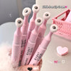 Pink lip cream with white applicators held by a hand, with a pink heart and basket in the background.