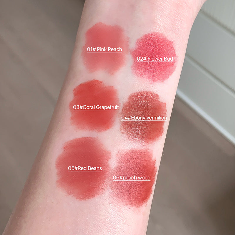 Lipstick swatches on a person's arm with color names and codes.
