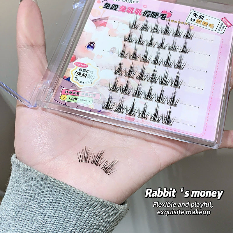 False eyelashes in packaging with a sample on skin, held by a hand.