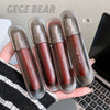 Five GEGE BEAR lip glosses held in a hand with a blurred laptop background