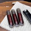 Three Gege bear lip glosses on a textured white surface with a wooden background.