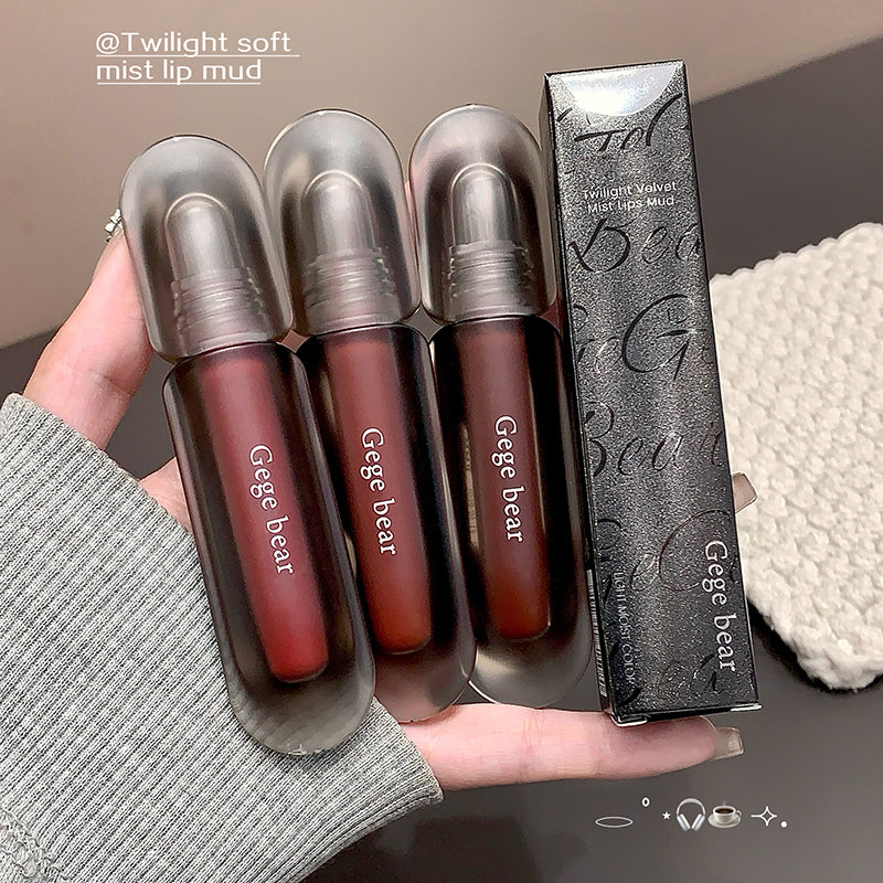 Three Gege bear lip glosses with their packaging held in a hand.