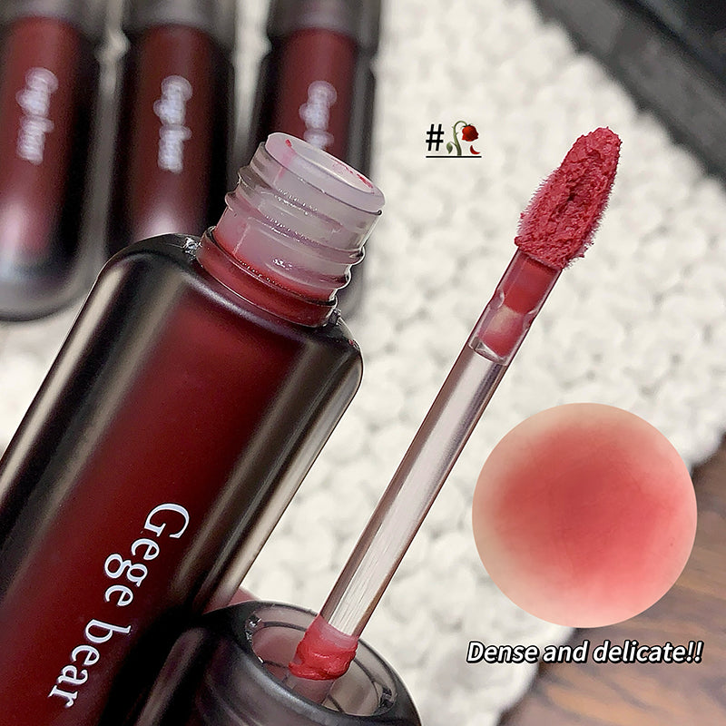 Lip gloss with applicator and swatch on a textured background, featuring the brand 'Gegebear'.