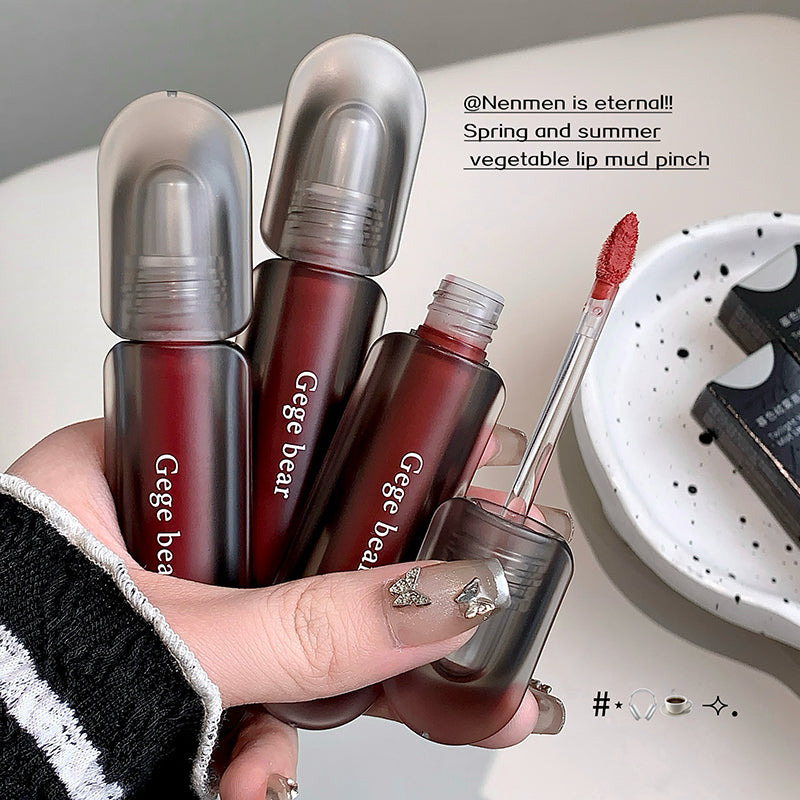 Hand holding Gege bear lip products with a brush and bowl in the background