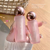 Two pink lip products with gold caps held by a hand against a neutral background