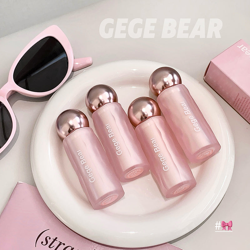 Pink lip products with 'GEGE BEAR' branding on a white plate, surrounded by sunglasses and packaging.