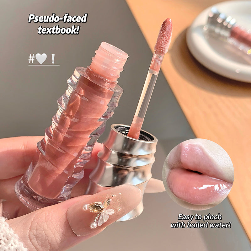 Clear lip gloss with pink shade being applied to lips, on a neutral background.