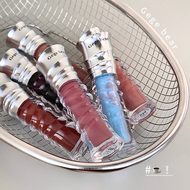 Set of lip glosses in various colors on a metal mesh surface with 'Geege beat' branding.