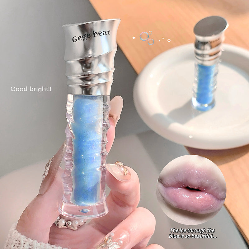 Blue lip gloss with silver cap held by a hand, close-up of lips with gloss applied.