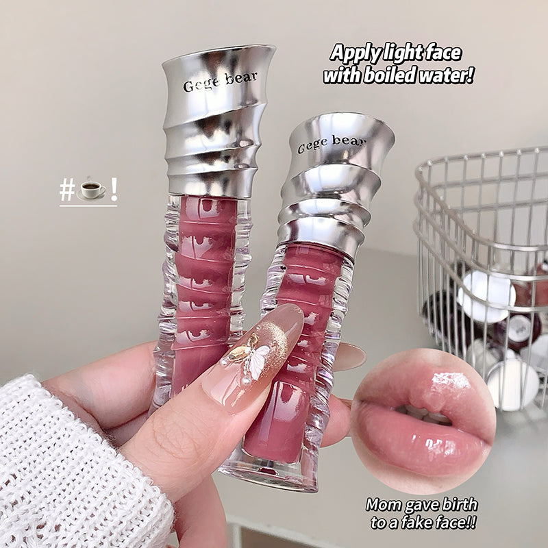 Two lip glosses with silver caps held by a hand, with text and an inset of lips wearing the gloss.