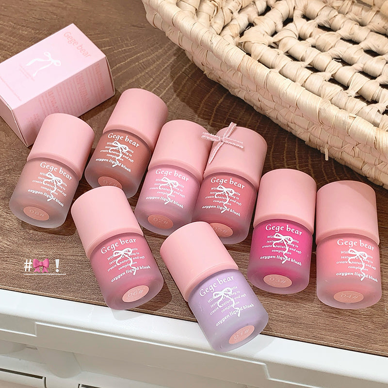 Set of pink lip balm tubes with visible brand name on a wooden surface.
