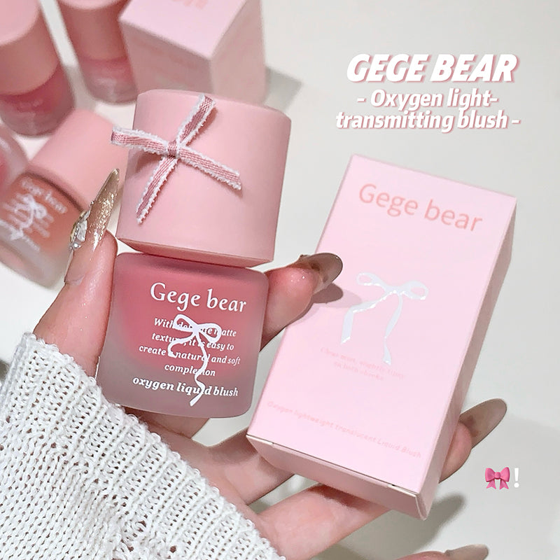 Pink Gege Bear oxygen liquid blush held by a hand with a matching box on a light background