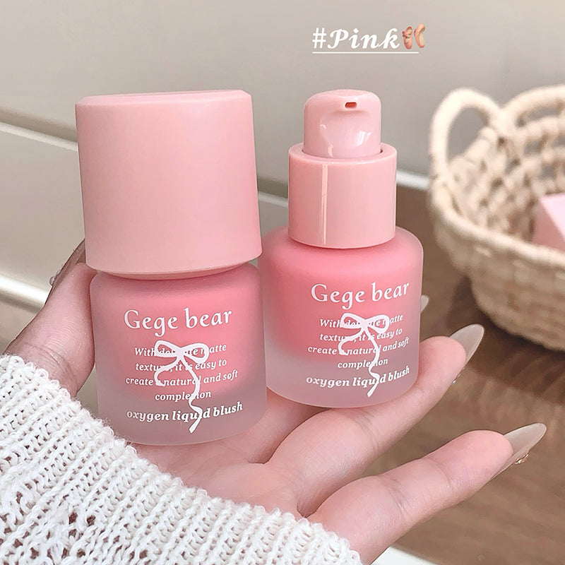 Two pink bottles labeled 'Gege bear' held in a hand with a blurred background.