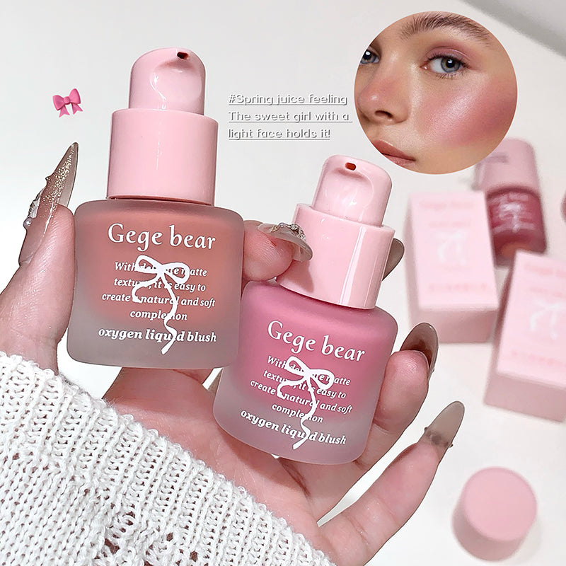 Two pink Gege bear makeup products held by a hand with a blurred face in the corner.