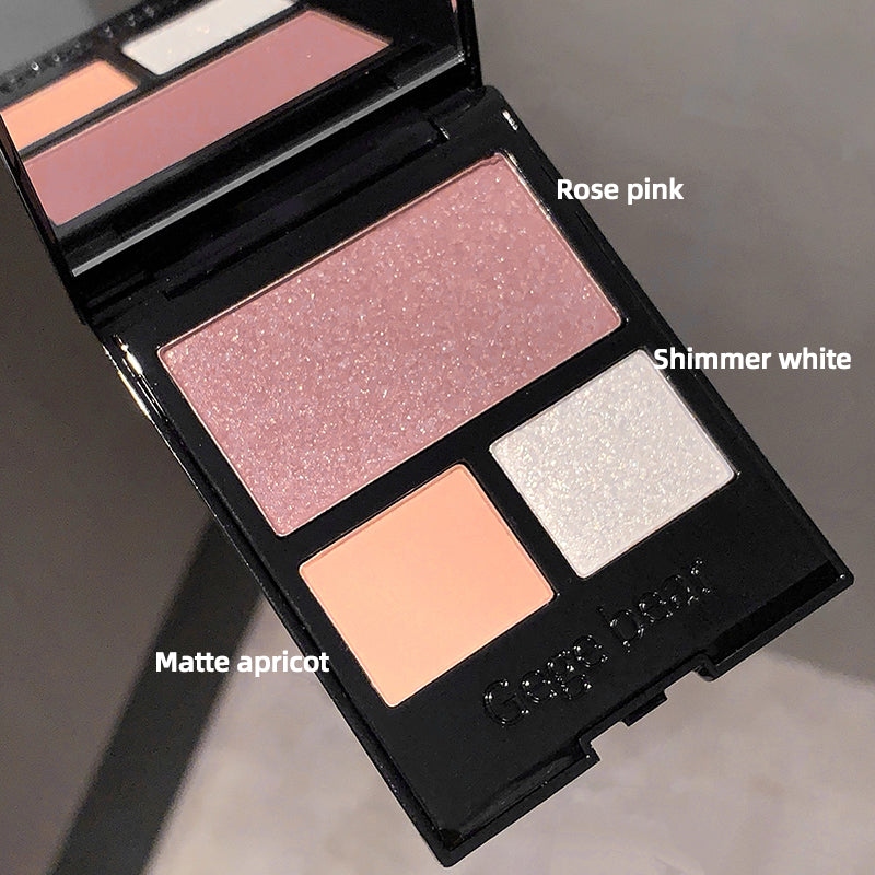 Makeup palette with rose pink, shimmer white, and matte apricot shades on a neutral background.