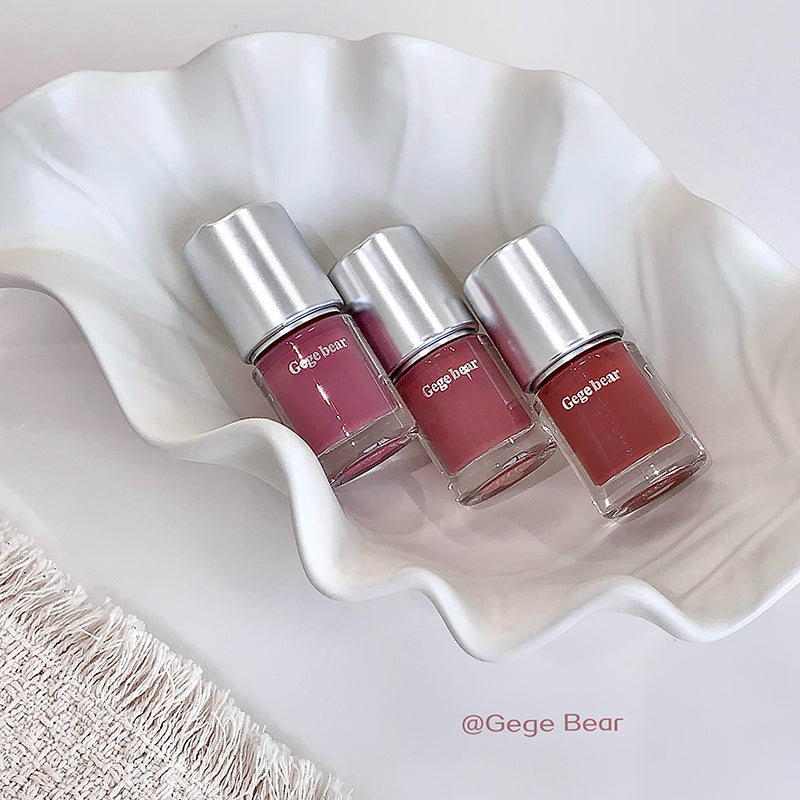 Three bottles of Gege Bear nail polish on a white wavy surface.