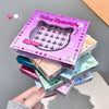 Stack of false eyelash boxes with a pink box on top, held by a hand.