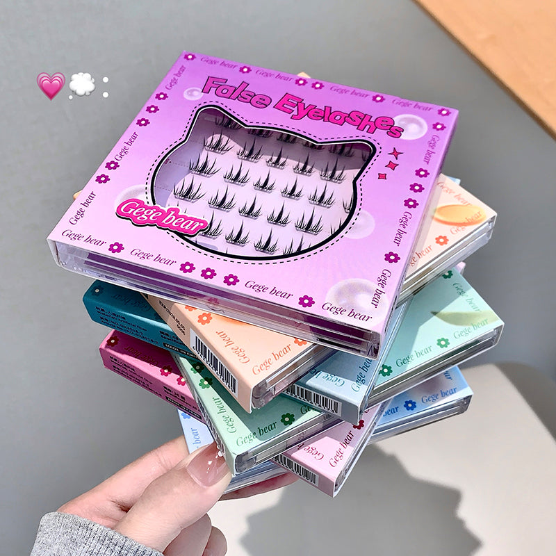 Stack of false eyelash boxes with a pink box on top, held by a hand.