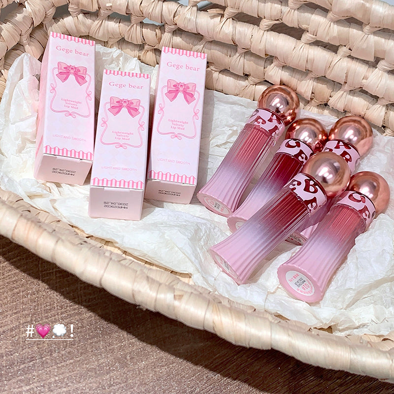 Pink lip gloss with packaging on a woven surface