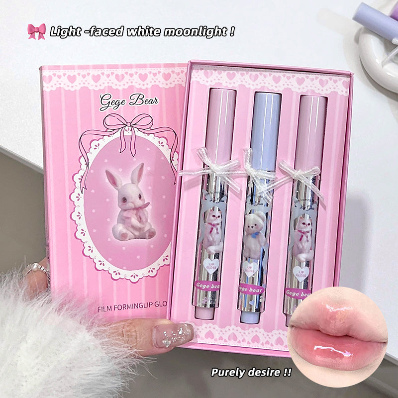 Pink lip gloss set with bunny design in a decorative box, held by a hand.