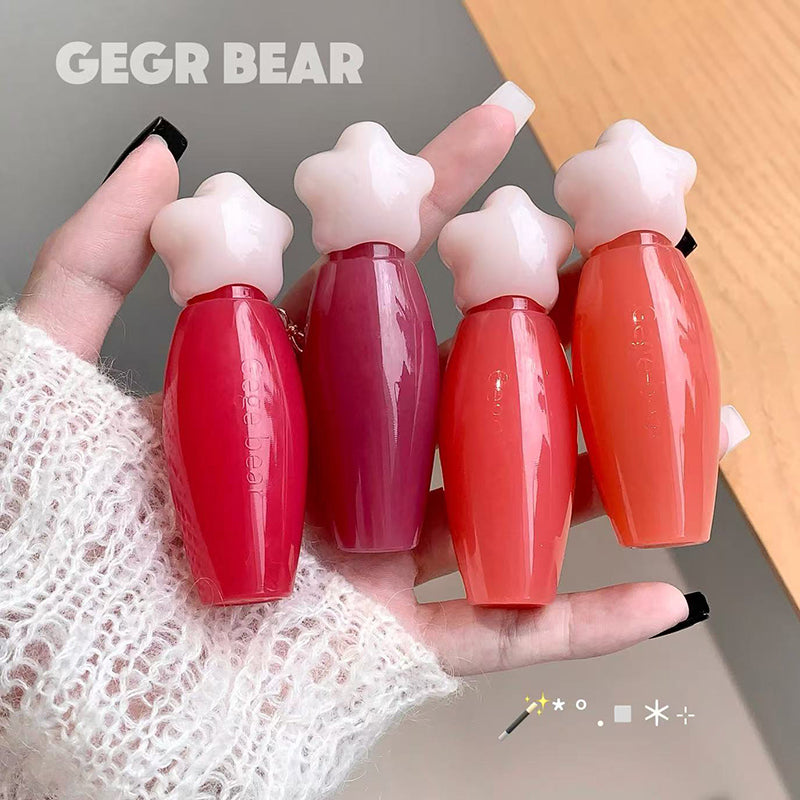 Four small red bottles with white caps held in a hand, branded 'GEGR BEAR'.