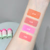 Lipstick swatches on a person's arm with labeled colors and lipsticks in the background.